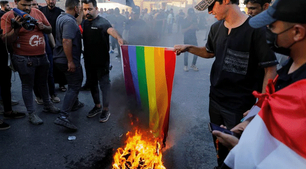 Foto destque: manifestantes iraquianos incendeiam bandeira LGBT+ em Bagdá, no fim de julho. Reprodução/Khalid Al-Mousily/Reuters